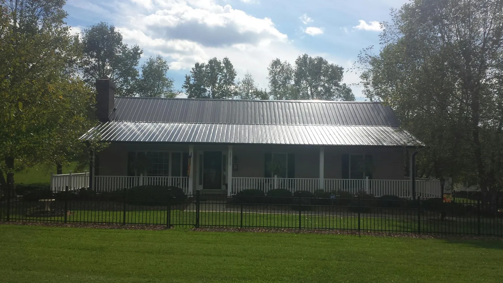 Gray metal roof on a brick ranch with a full width front porch — Gutter Guard Installation work by our crew in Mount Hope