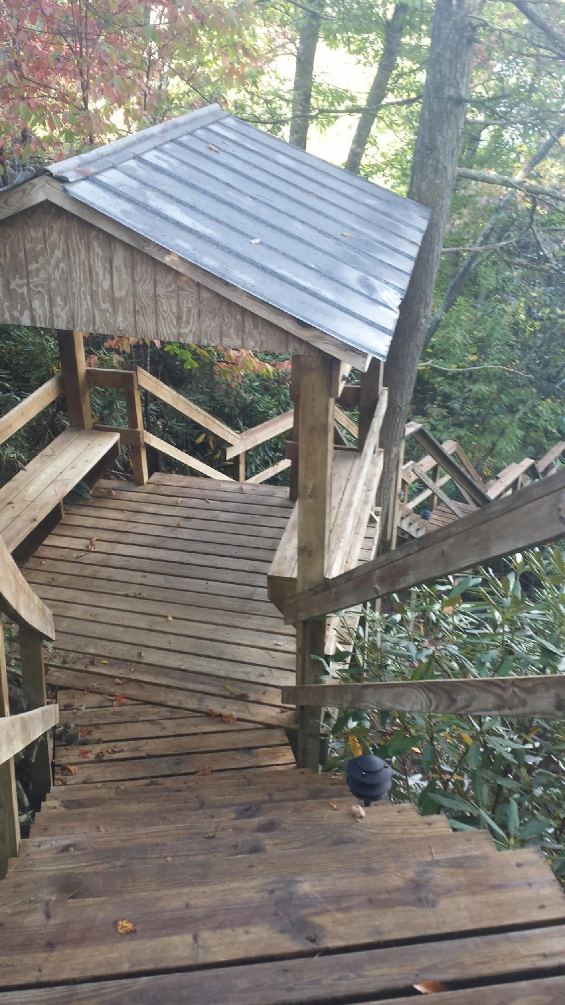 Metal roofed shelter over wooden steps on a wooded walkway — Skylight Repair & Installation work by our crew in Mount Hope